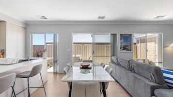 A modern kitchen with a dining area, a sofa, and a view of the outside.