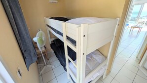 Een slaapkamer met een stapelbed, een ventilator, een raam en uitzicht op buiten.