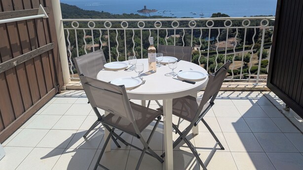 Een ronde tafel met stoelen op een balkon met uitzicht op zee.