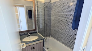 Een badkamer met een bad, wastafel en douche.