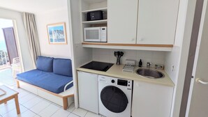 Een praktische keuken met een ingebouwde wasmachine, een magnetron en een spoelbak.