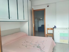 Un dormitorio con cama, escritorio y armario.