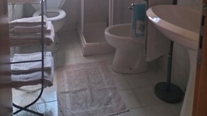 Une salle de bain avec des toilettes, une douche, un lavabo et une fenêtre.