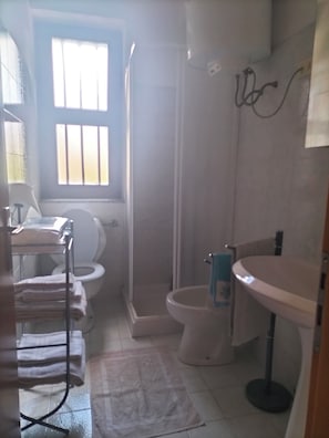 Un baño con inodoro, ducha, lavamanos y ventana.