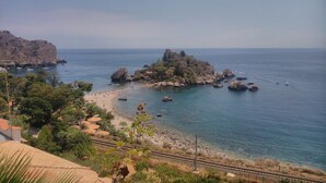 Un paysage côtier avec une île rocheuse, une plage et un ciel dégagé.