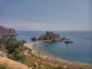 Un paisaje costero con una isla rocosa, una playa y un cielo despejado.
