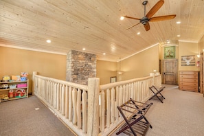 A wooden ceiling with a ceiling fan, a stone fireplace, a wooden railing, and a staircase. - Bright Mountain Cabin with Private Fire Pit near Yellowstone in Island Park, Idaho (Island Park)