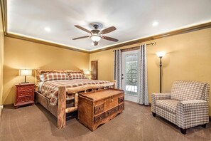 A bedroom with a bed, a wooden bench, a nightstand, a chair, and a ceiling fan. - Bright Mountain Cabin with Private Fire Pit near Yellowstone in Island Park, Idaho (Island Park)