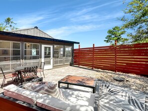 Un patio con mobiliario exterior, una cerca roja y un edificio con ventanas amplias.