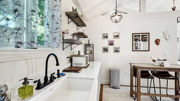 A modern kitchen with a white sink, black faucet, and wooden shelves.