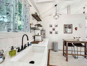 Una cocina moderna con un lavamanos blanco, grifo negro y estantes de madera.