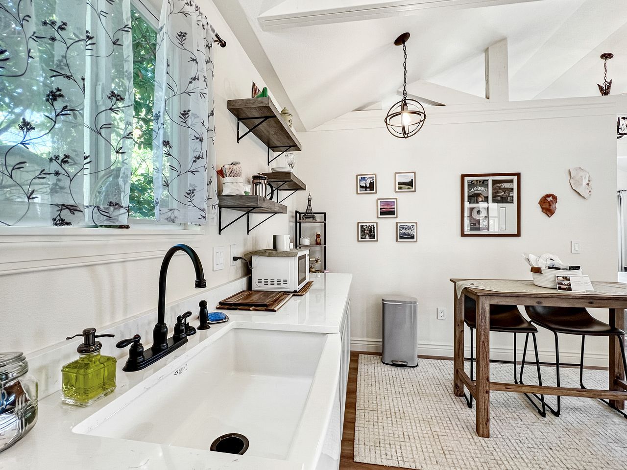 Eine moderne Küche mit einem weißen Spülbecken, einem schwarzen Wasserhahn und Holzregalen.