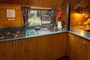 A kitchen with wooden cabinets, a sink, a stove, and a window with curtains.