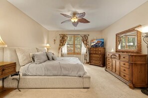 A bedroom with a bed, a dresser, a mirror, a ceiling fan, and a window with curtains. - Upscale Mountain Retreat with Cozy Fireplace & Jetted Tub in Alpine, Utah (Alpine)