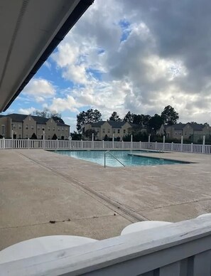 A swimming pool with a white fence, surrounded by buildings and trees under a cloudy sky. - Pool Days & Golf Getaways in Myrtle Beach (Myrtle Beach)