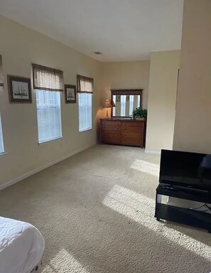 A room with a bed, a dresser, a television, and framed pictures on the wall. - Pool Days & Golf Getaways in Myrtle Beach (Myrtle Beach)