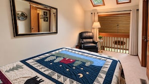 A bedroom with a bed, a chair, a nightstand, a window with curtains, and a balcony with a railing. - Fairfield Lakefront Getaway (Jackson County)