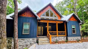 A two-story house with a stone foundation, a porch with wooden railings, and a steeply pitched roof. - Celastrina Cottage of Sapphire Valley (Jackson County)
