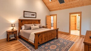 A bedroom with a wooden bed, nightstands, a rug, and a framed picture on the wall. - Celastrina Cottage of Sapphire Valley (Jackson County)