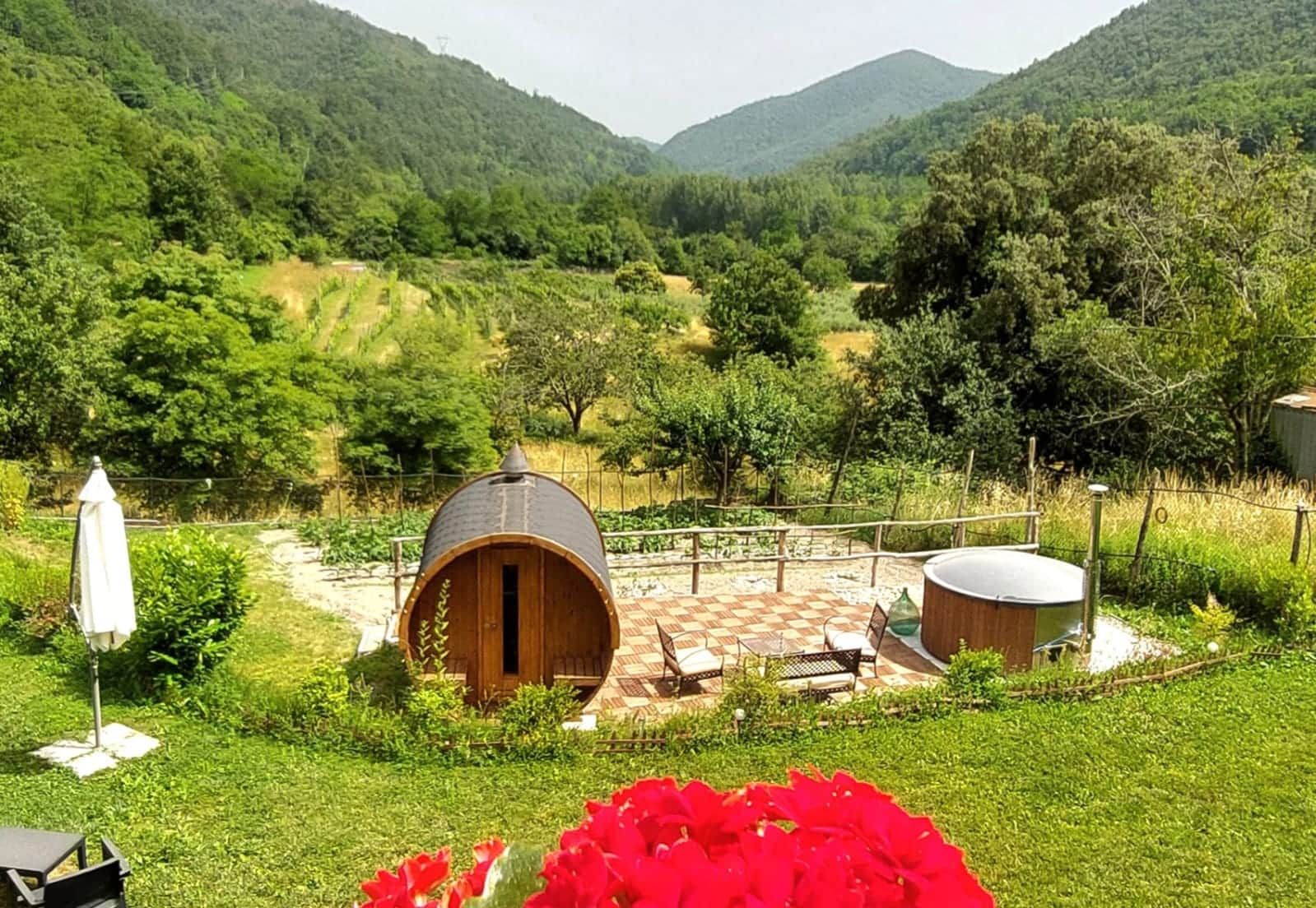 Un'ambientazione rustica all'aperto con una struttura in legno a botte, un patio a scacchi e vista su una valle rigogliosa.