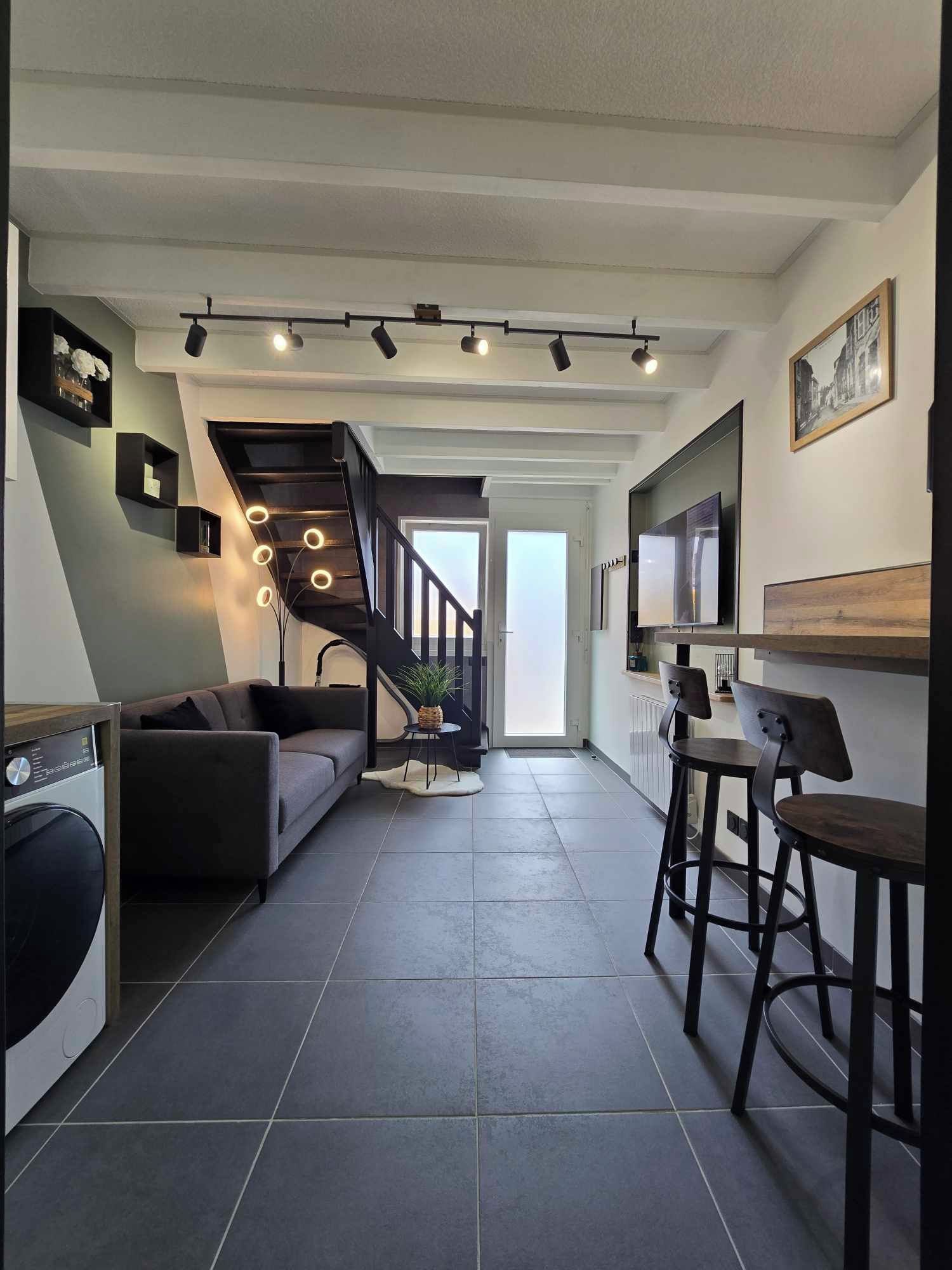 Een modern interieur met een trap, een bank, een eethoek en een keuken.