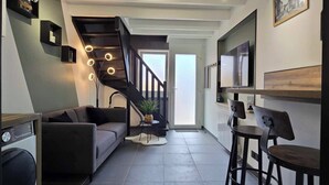 Een modern interieur met een trap, een bank, een eethoek en een keuken.