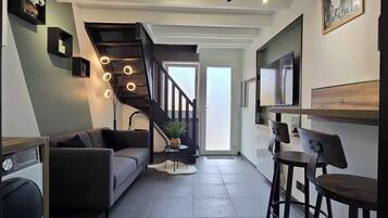 Een modern interieur met een trap, een bank, een eethoek en een keuken.