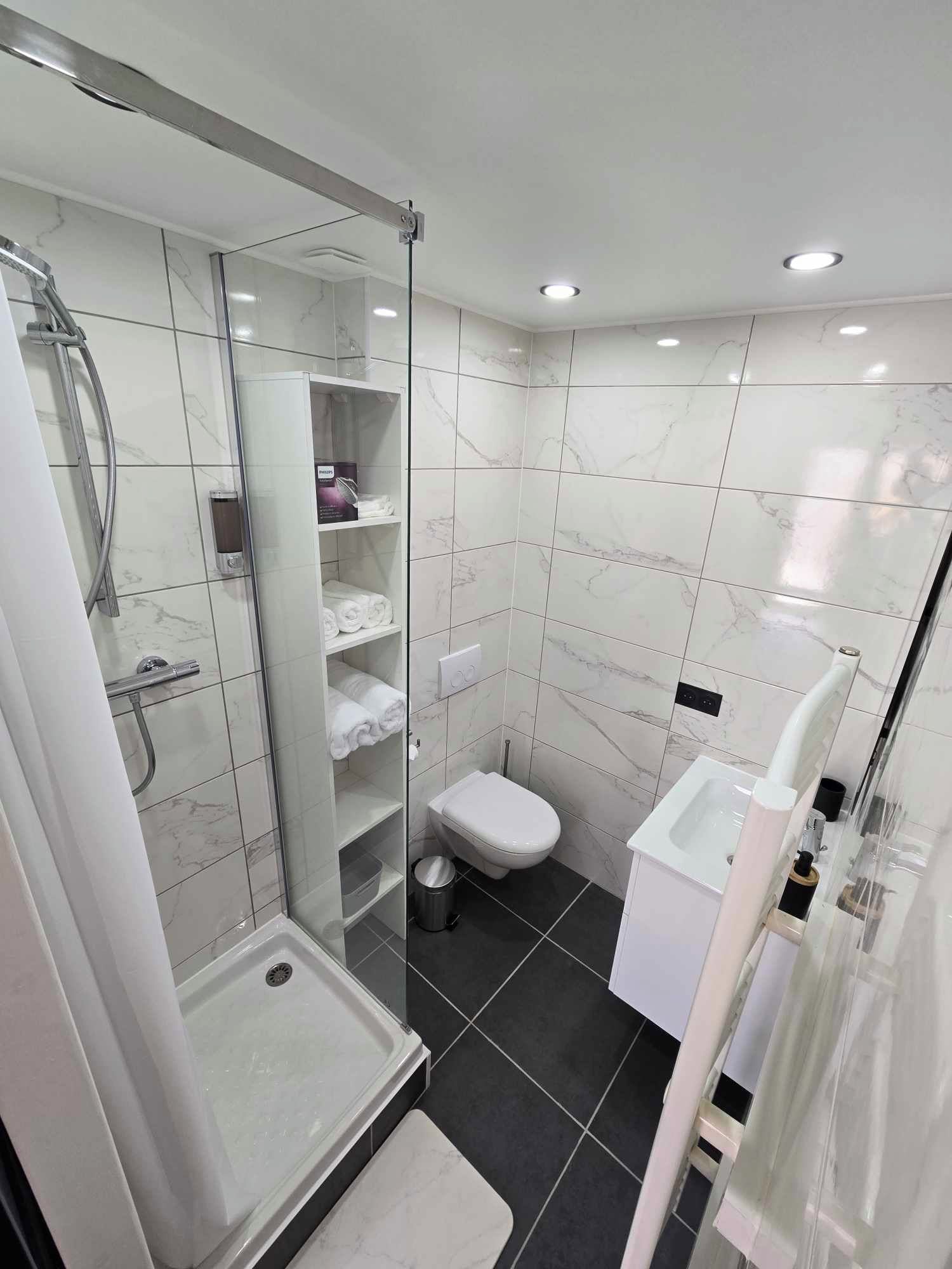 Een moderne badkamer met een douchecabine van glas, een toilet en een bidet.