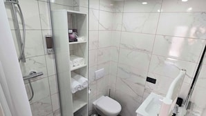 Een moderne badkamer met een douchecabine van glas, een toilet en een bidet.
