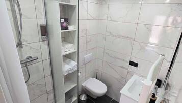 Een moderne badkamer met een douchecabine van glas, een toilet en een bidet.