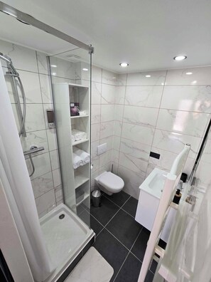 A modern bathroom with a glass-enclosed shower, a toilet, and a bidet. - New apartment near the Outlet Village (La Verpillière)
