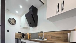 Een moderne keuken met een ingebouwde wasmachine, een klok aan de muur en een houten aanrecht.