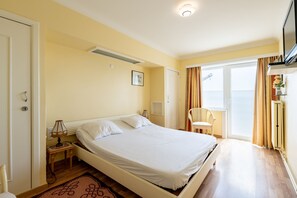 A hotel room with a bed, a chair, a desk, a TV, and a window with curtains. - Apartment on Zeedijk With North Sea Views (Blankenberge)