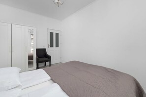 Ein Schlafzimmer mit einem Bett, einem Sessel, einem Kleiderschrank und einer Tür.