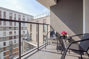A balcony with a glass railing, a table with two chairs, and a potted plant. - Apartament z Balkonem na 10 Pietrze w Lodzi by Noclegi Renters (Łódź)