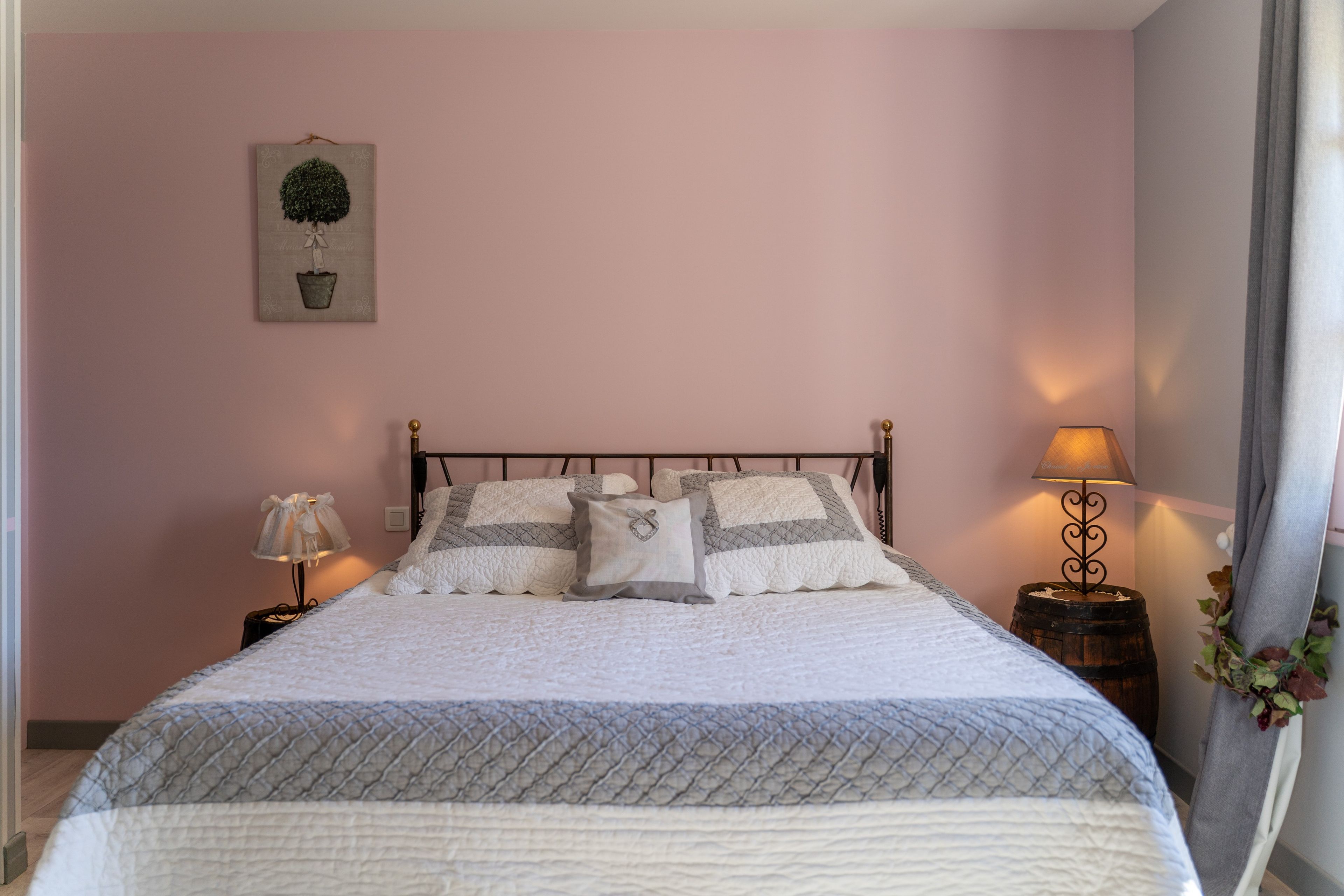 A neatly made bed with a quilted bedspread, two pillows, and a decorative wall hanging.