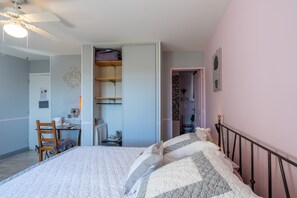 A bedroom with a bed, a desk, and a chair. There is a wardrobe and a door leading to a bathroom.