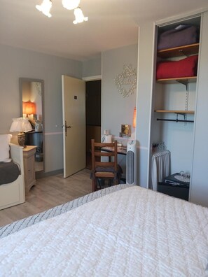Une chambre à coucher comprenant un lit, un bureau, une chaise, une armoire et une table de chevet.