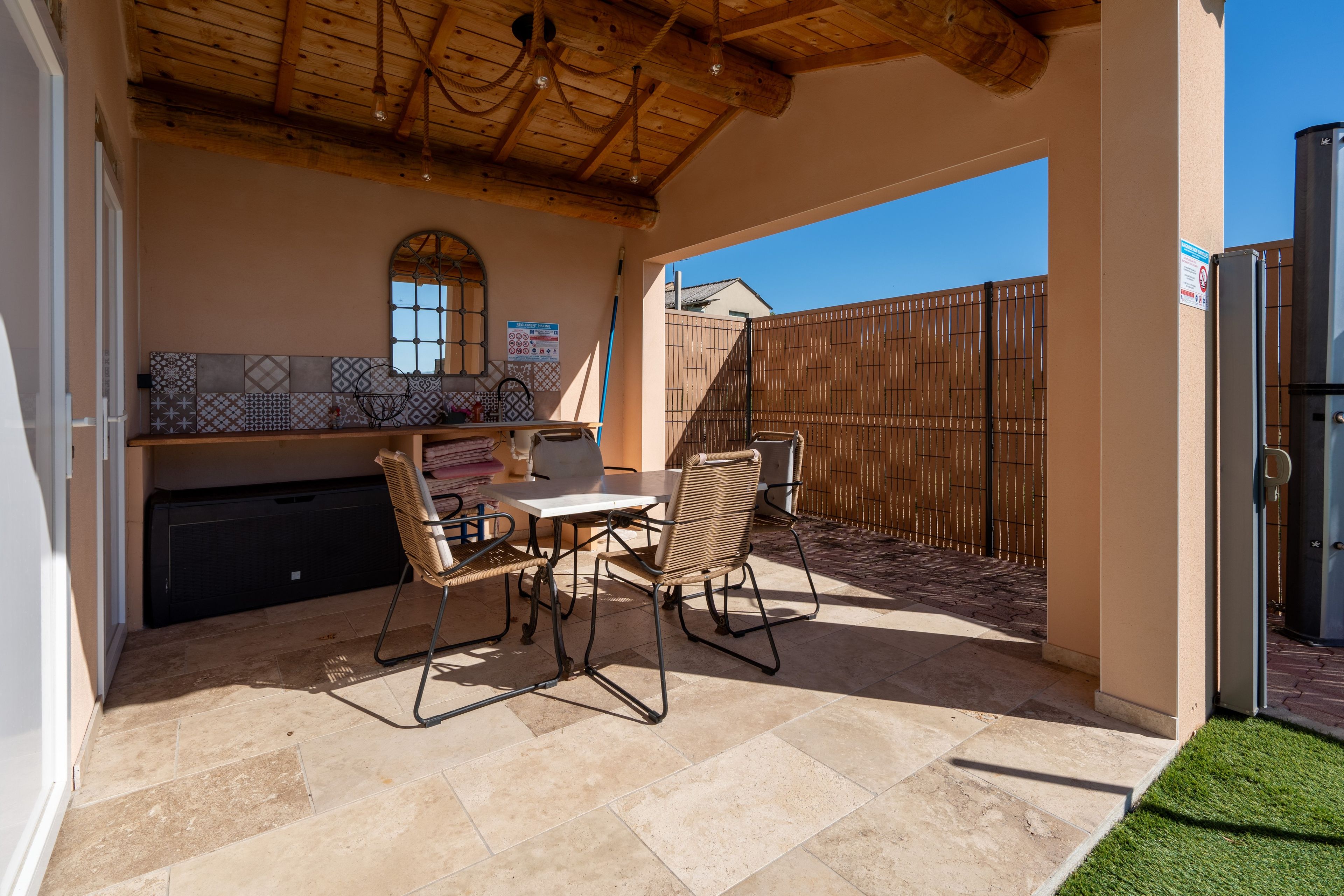 Eine Terrasse im Freien mit Tisch und Stühlen, einer Fliesenverkleidung und einer Holzbeschichtung.