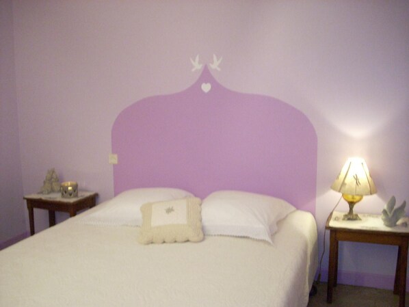 Une chambre à coucher comprenant un lit, deux tables de chevet, une lampe et un élément décoratif mural.