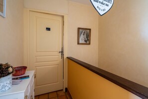 A hallway with a closed door, a framed photograph on the wall, and a sign above the door.