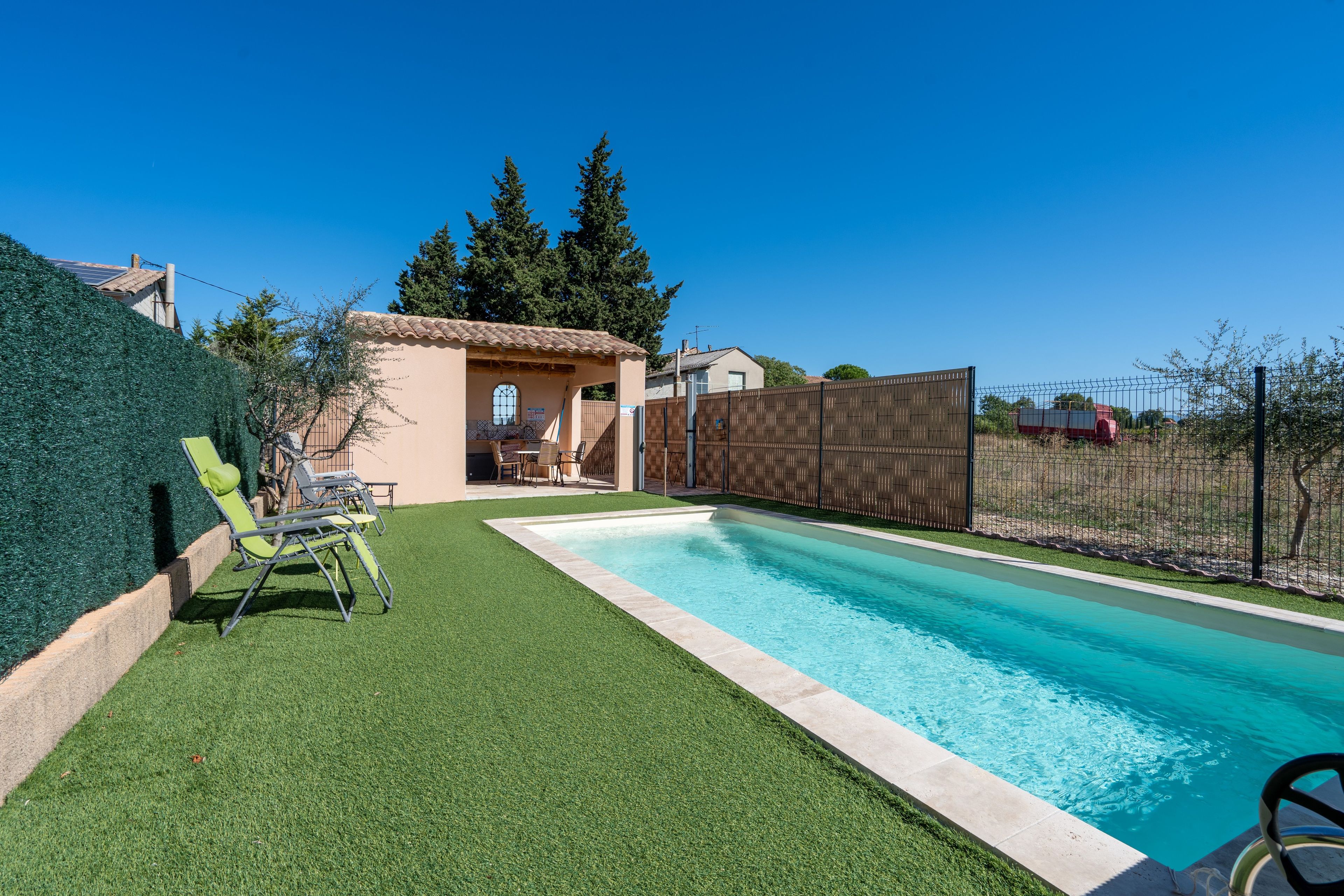 Ein Garten mit Pool, Kunstrasen und einem eingezäunten Bereich.