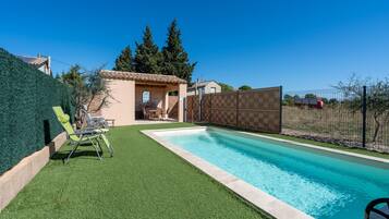 Ein Garten mit Pool, Kunstrasen und einem eingezäunten Bereich.