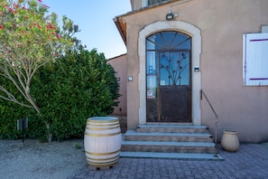 A building with a stone facade, a wooden door with a glass panel, and steps leading to the entrance.