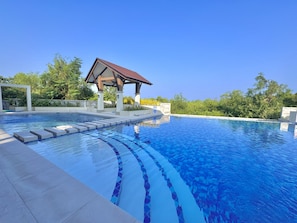 A swimming pool with a tiled edge, a covered pavilion, and surrounding greenery. - Royal Oceancrest Panglao 1 (Dauis)