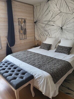Ein Schlafzimmer mit einem großen Bett, einer Bank, einem Wandbild und einer Wand mit Muster.