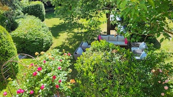 Un jardin agrémenté d’un espace détente, d’une mangeoire pour oiseaux et d’une variété de plantes et de fleurs.