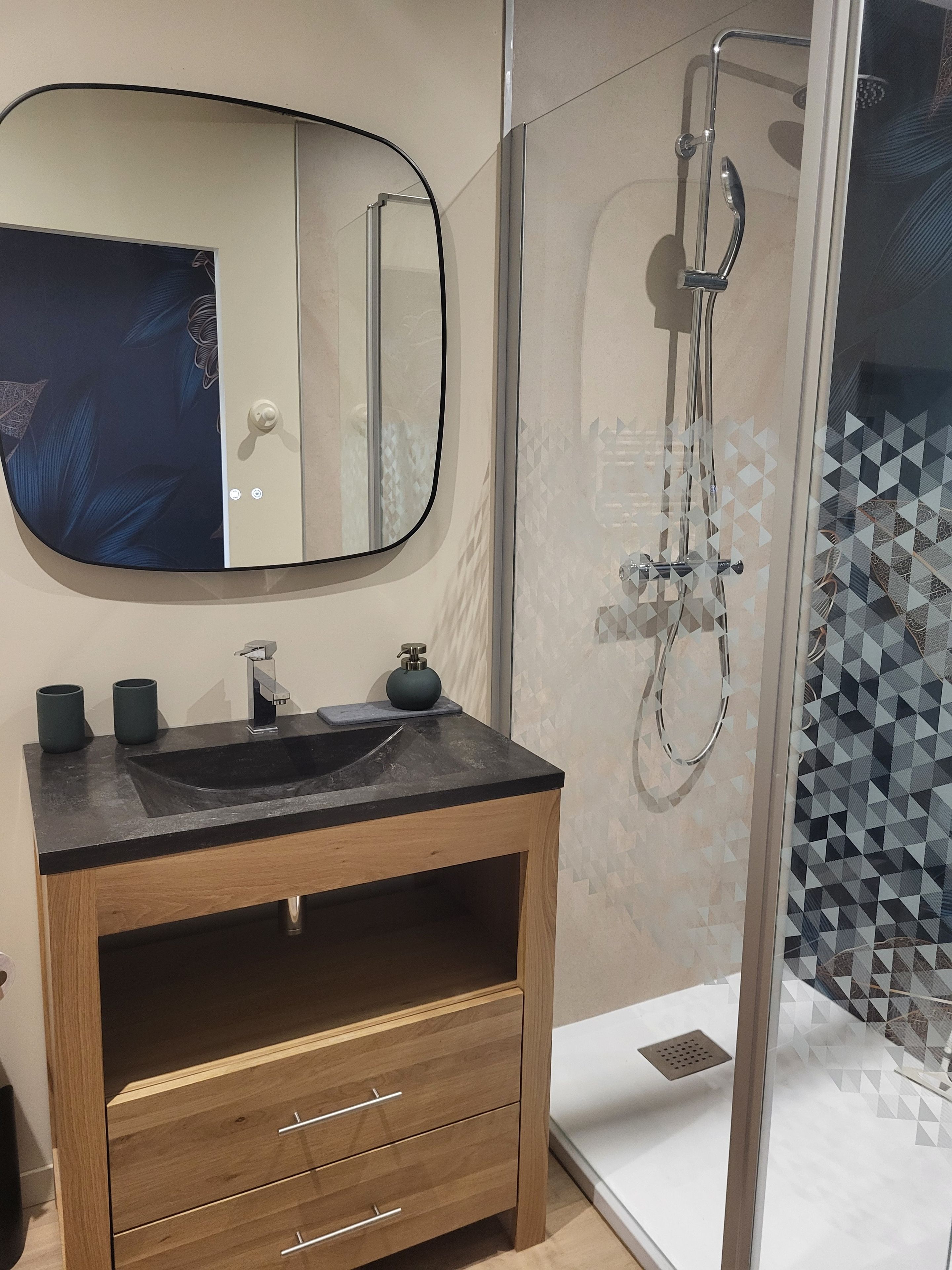 A bathroom with a black sink, wooden vanity, and a glass shower enclosure.
