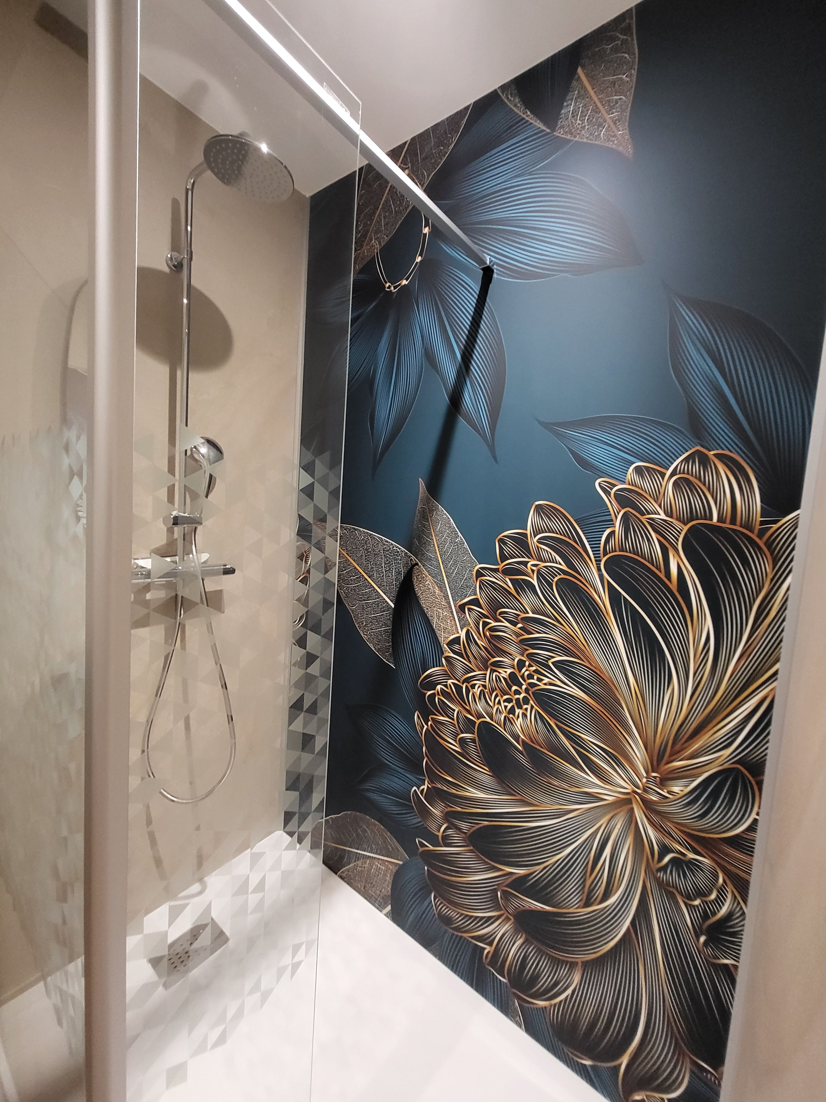 A shower with a glass door, a handheld showerhead, and a wall-mounted control panel.