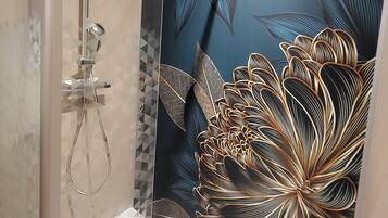 A shower with a glass door, a handheld showerhead, and a wall-mounted control panel.